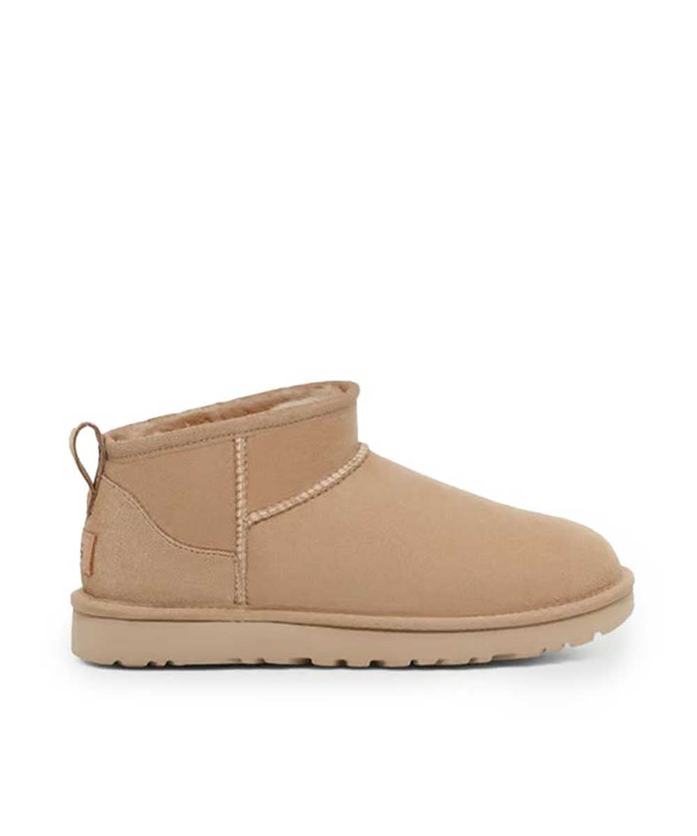 A single light tan suede ankle boot with a pull tab and whipstitch detailing, shown in a side profile on a white background.